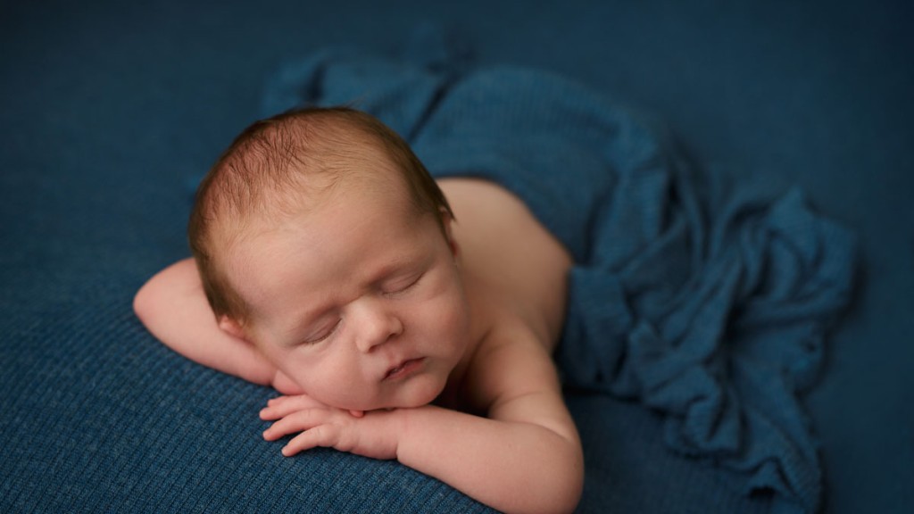 forward facing little baby boy on teal blanket