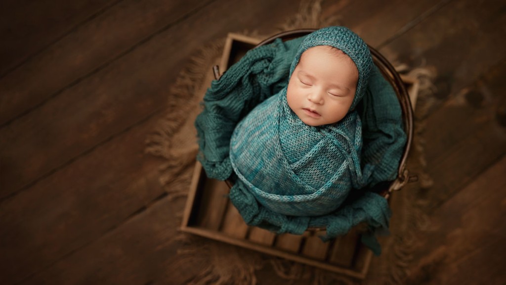 Shelly Rosen swaddled this baby boy in a teal knit wrap for this wrapped bucket pose. Prop poses are so much fun!