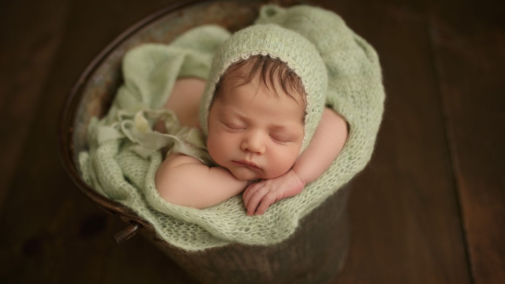 Newborn baby sleeping in a bucket forward facing.