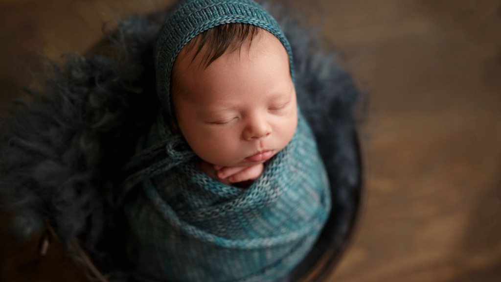Baby boy's hair shows from under his bonnet keeping him cozy. Swaddled in a matching knot wrap, he is posed in an antique bucket with a matching felted fur. Safety always comes first for this San Marcos newborn photographer, Shelly Rosen.
