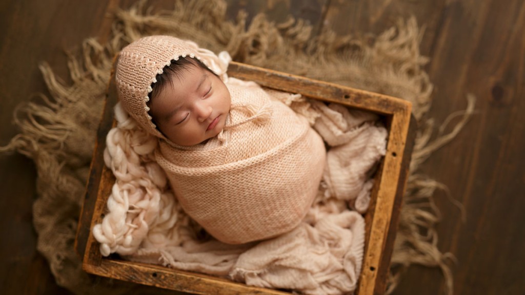 san diego newborn swaddled in a pink knit wrap and posed in an antique crate. Image taken by Shelly Rosen in her San Marcos newborn photography studio.